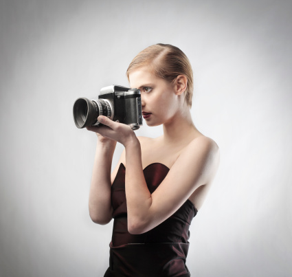 Beautiful elegant woman wearing an evening gown and using a camera