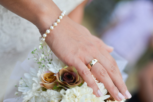 Gold ring on a ginger .Wedding bouquet of flowers in brides' hands