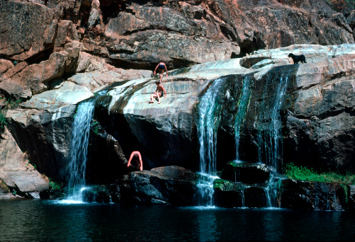 Three boys and a dog enjoy a beautiful swimming hole with waterfalls and plenty of sunshine.  Richly colored rocks and water show off in this 35mm Kodachrome film scan.