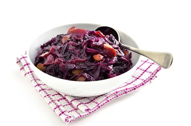 Warm and spicy red cabbage with apple in white dish on white background