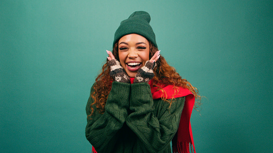 Excited young woman squeals with hands under chin, Cozy winter Christmas studio. High quality photo