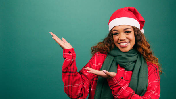 istock Beautiful young woman gestures palms to copy space, Santa hat studio 1770931417