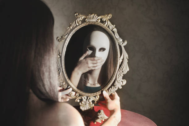 鏡の前でマスクをした女性が口の前で手を当てて静かにしている様子を映し出す、抽象的なコンセプト - mirror women reflection ghost ストックフォトと画像