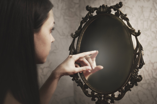 woman touches the reflection of herself in the mirror, abstract concept