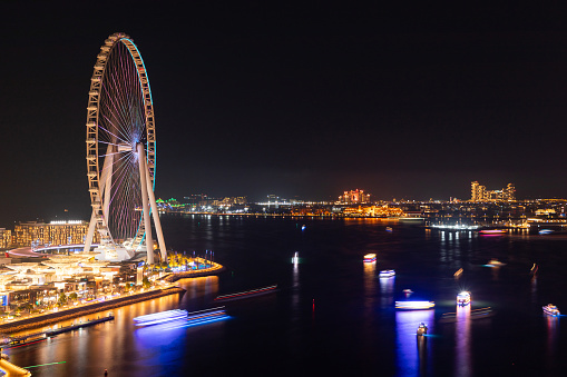 Dubai, United Arab Emirates - June 21, 2023: Ain Dubai Ferris wheel at night with Atlantis, The Palm hotel resort located at the apex of the Palm Jumeirah in the United Arab Emirates