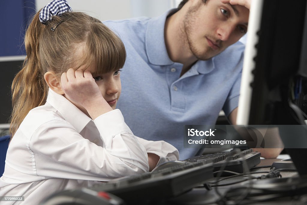 Infeliz maestro y niña utilizando el ordenador en clase - Foto de stock de Escuela primaria libre de derechos