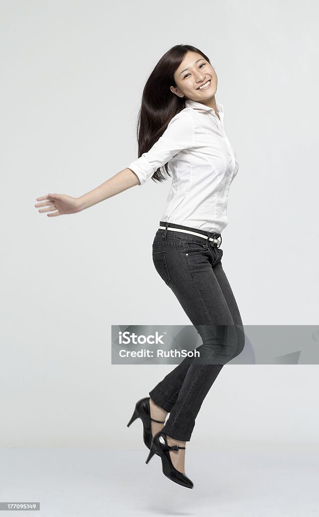 Jump for joy "Cheerful young Chinese lady jumping with a big smile, isolated on light grey background, motion blur on limbs." Businesswoman Stock Photo