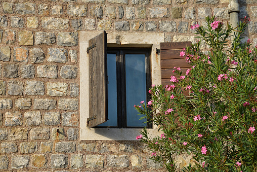 Part of an old stone wall and wooden window with flowers