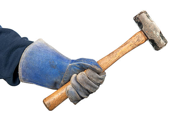 Man swinging hammer "A man holding a small beat up sledgehammer while wearing old, worn out workshop gloves." arm hammer stock pictures, royalty-free photos & images