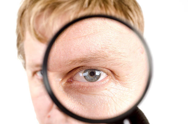 istock portrait of young man looking through a magnifying glass 177096940