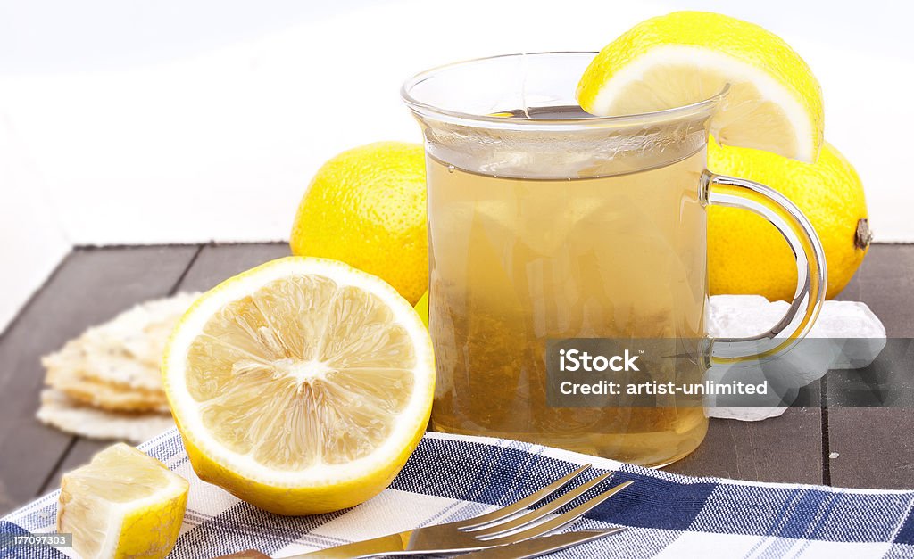 hot lemon tea "studio-shot of a glass with hot lemon tea, a slice of lemon and rock sugar, on a wooden tray." Alternative Medicine Stock Photo