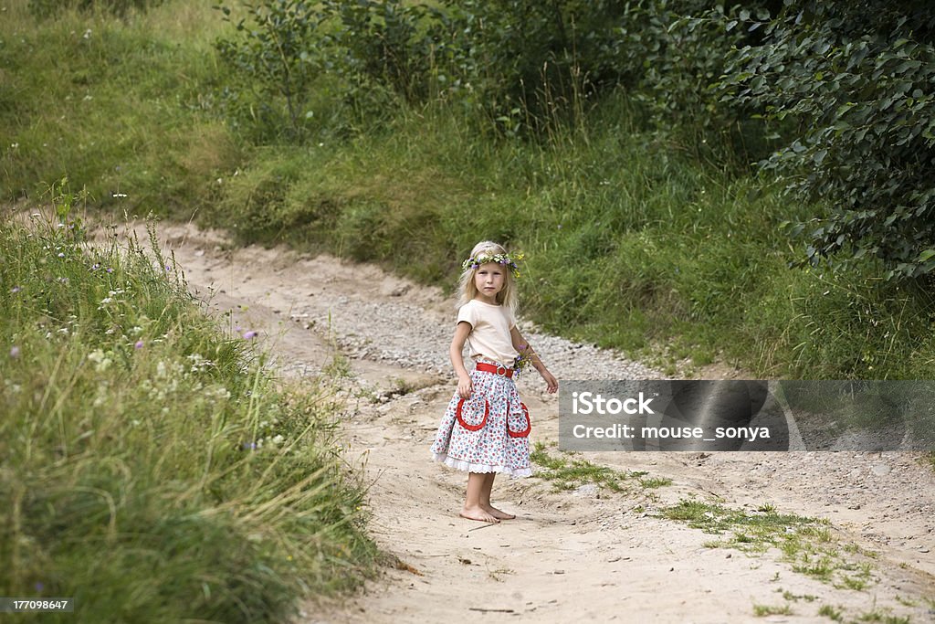 daughter of summer little girl in wild flowers wreath standing on road barefoot Active Lifestyle Stock Photo