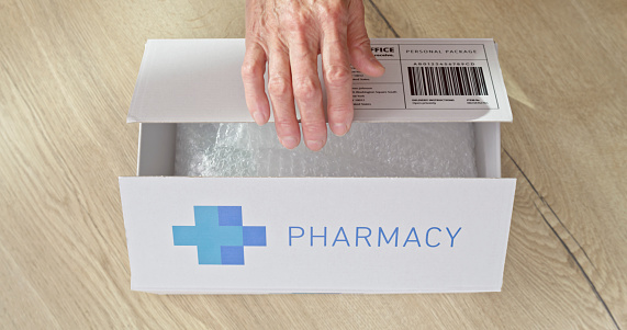 Close-up of woman's hand opening pharmacy box on table.