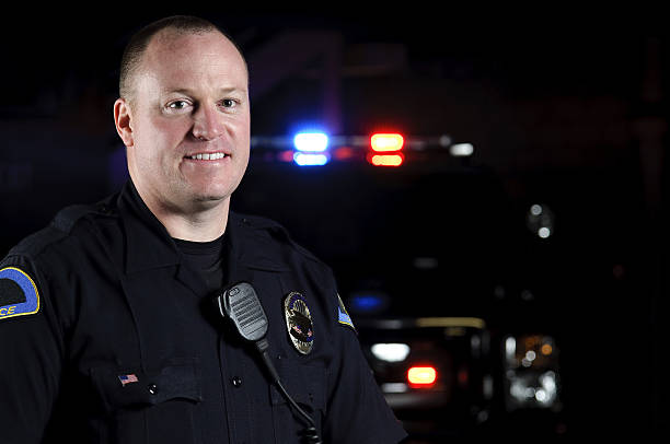 police officer a police officer standing in front of his patrol unit. police force smiling officer stock pictures, royalty-free photos & images