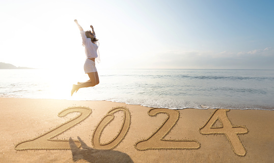 Woman jumping on new year number 2024 beach