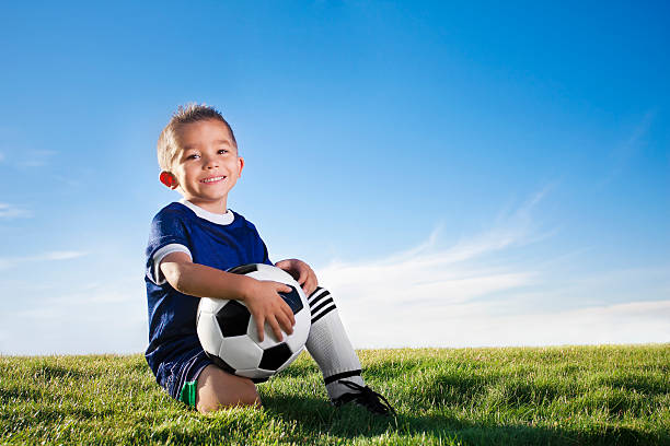 Portrait of a young boy wearing a soccer uniform in a field stock photo