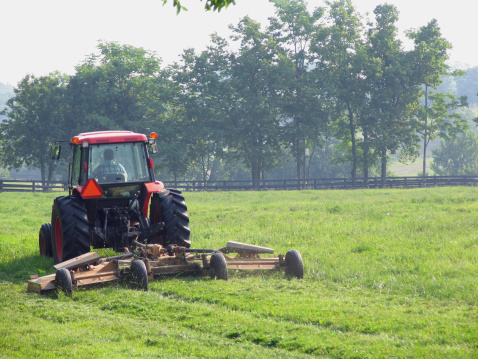 Farmer on tractor mowing field