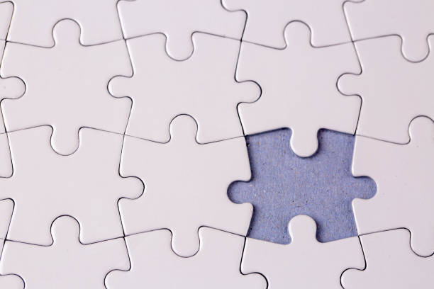 istock Missing jigsaw puzzle pieces. Business concept. Fragment of a folded white jigsaw puzzle and a pile of uncombed puzzle elements against 1771015897