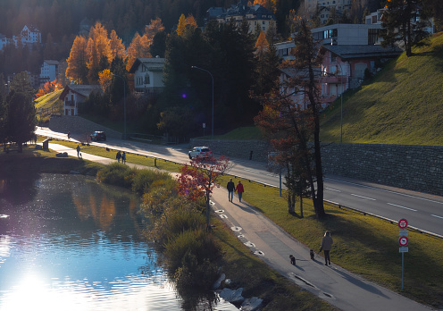 Magnificent autumn atmosphere of St.Moritz, famous and luxury ski resort town, located in the upper Engadin valley in the south-eastern corner of Switzerland. People walking along the lake on footpath.