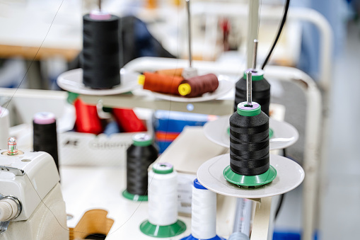 Sewing accessories in a basket and spools of threads next to sewing machine