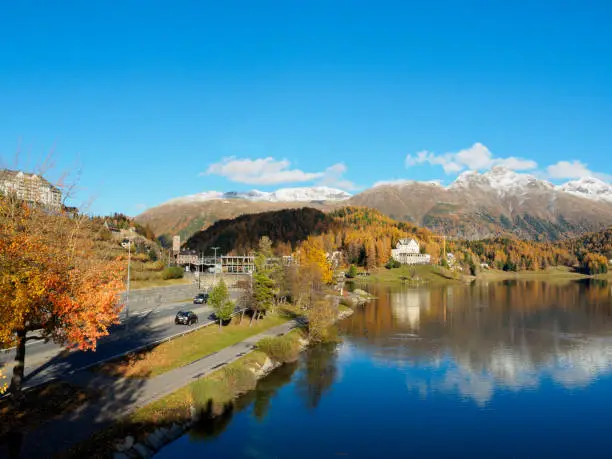 Magnificent autumn atmosphere of St.Moritz, famous and luxury ski resort town, located in the upper Engadin valley in the south-eastern corner of Switzerland. See road and footpath run alongside the lake.
