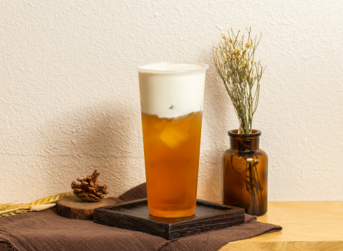 Iced Classic original milk green tea served in disposable glass isolated on wooden board side view of taiwanese ice drink