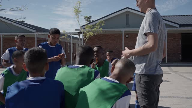 Teacher talking with an elementary boy's soccer team after a school practice