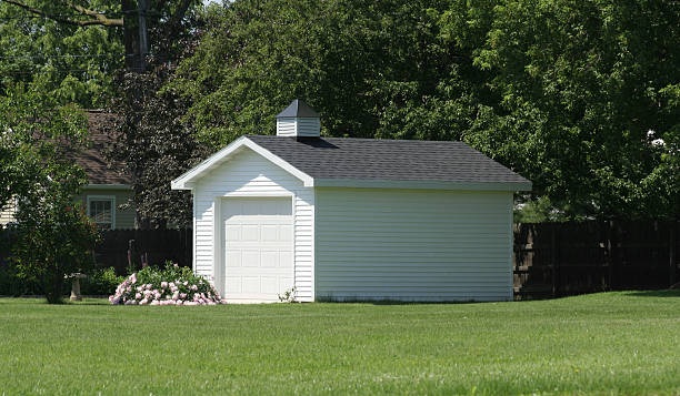 Storage Shed with garage door "Storage shed featuring home like amenities including vinyl siding, single stall garage door and asphalt shingles." detached house stock pictures, royalty-free photos & images