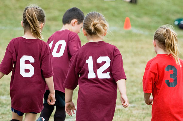 vier kinder spielen fußball - soccer action child purple stock-fotos und bilder