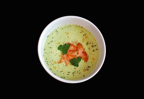 Photo of Avocado soup with salmon slices on a black background