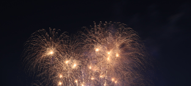 A golden colored fountain firework exploding high in the air like fire, with sparks flying every.
