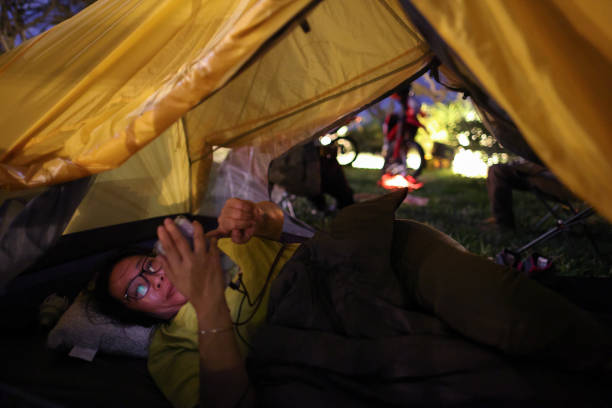 Night time woman lying in tent and using mobile phone before going to bed