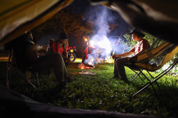 A group of young happy friends sitting by the fire at summer alpine camping and enjoying a moment of freedom away from the hustle and bustle