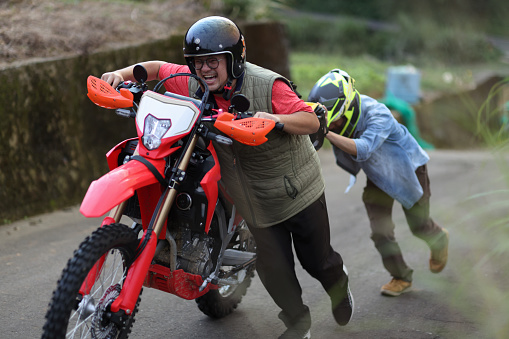 Two men worked together to Pushing the broken down motorcycle uphill while the motorcycle was camping.