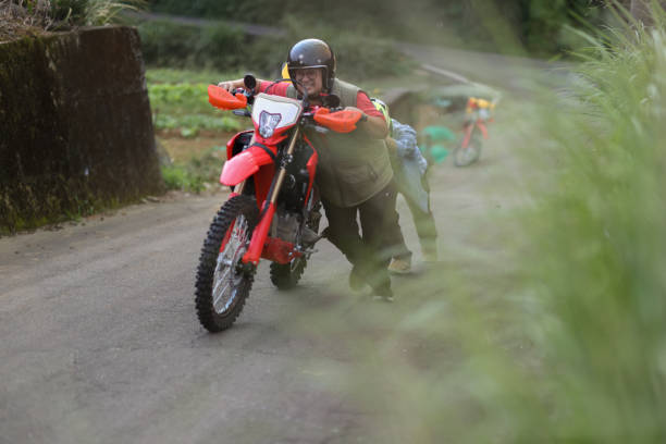 Two red off-road motorcycles parked on dry terrain with helmets resting on the handlebars in rugged outdoor conditions