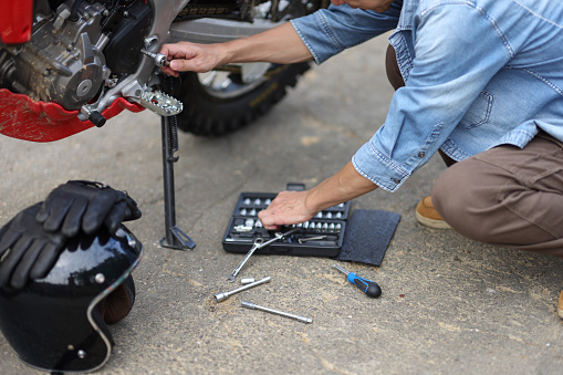 One man is troubleshooting a motorcycle problem while on a motorcycle camping trip