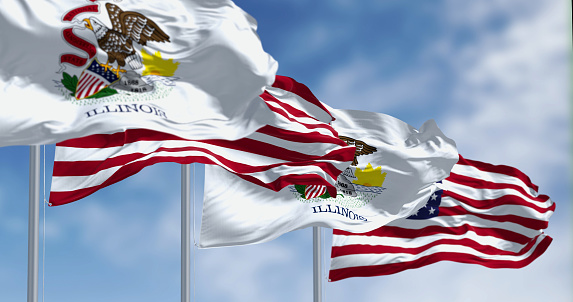 Illinois state flags waving with the national flag of the American flags on a clear day. US state flag. Pride and patriotism concept. 3D illustration render. Fluttering fabric. Selective focus
