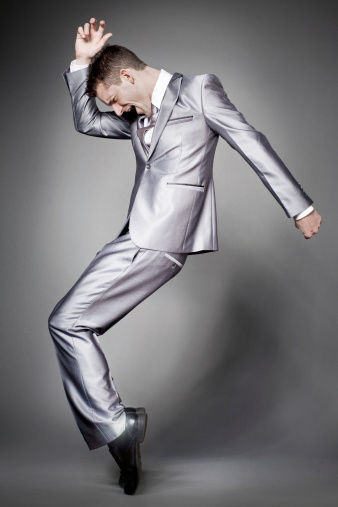 Young dancing  businessman in elegant gray suit.