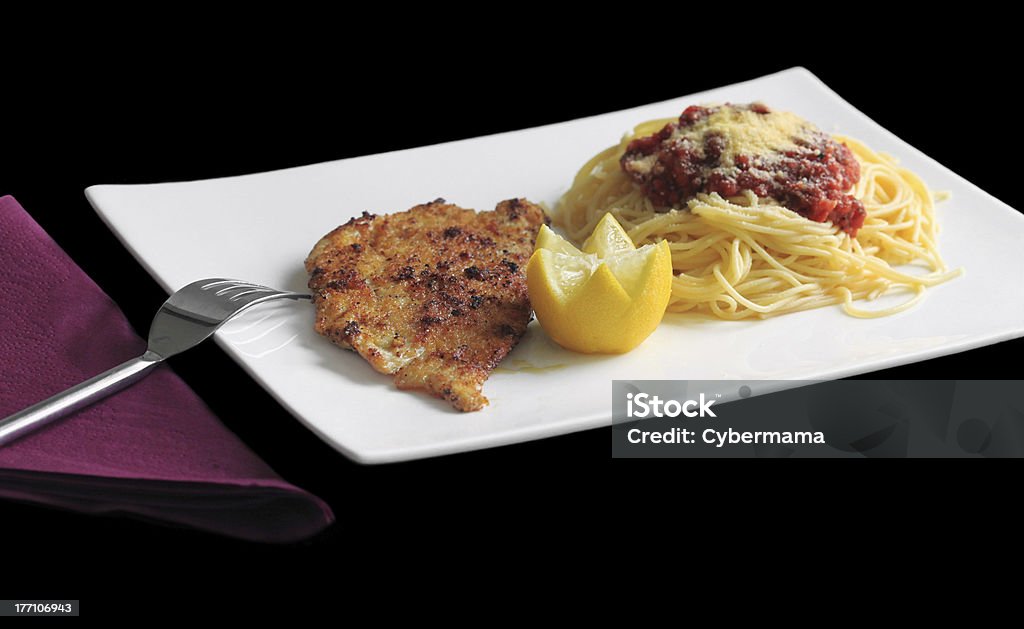 Milanese escalopes "Veal (or chicken) escallop served with spaghetti and tomato sauce, Parmesan cheese and lemon. Shot on black background." Black Background Stock Photo