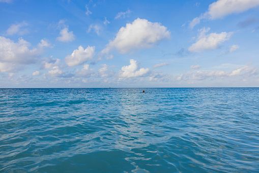 Stunning view of Caribbean sea blue waters in Aruba against backdrop of clear blue skies with white fluffy clouds.