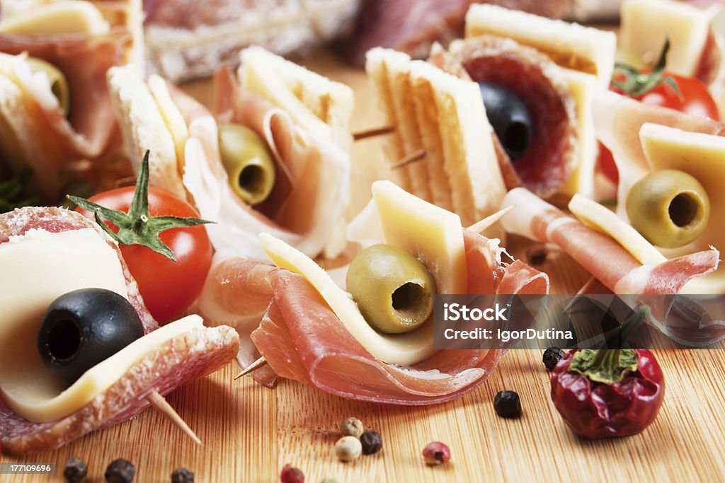 Prosciutto and salami canape "Prosciutto, salami, cheese and olive canape appetizer on wooden board" Antipasto Stock Photo