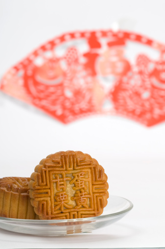 Chinese moon cakes on a plate with Chinese paper cutting background