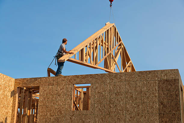 Roof Trusses Being Hoisted Onto Unfinished Home Frame stock photo