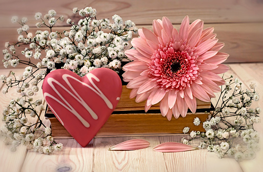 Pink gerbera flower and heart. Concept for Valentine s Day. Old books and gypsophila flowers as decor on a light background.