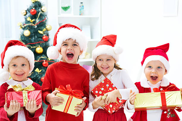 Kids in Christmas outfits posing happily with their gifts stock photo