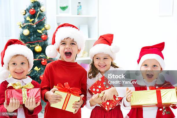 Kids In Christmas Outfits Posing Happily With Their Gifts Stock Photo - Download Image Now