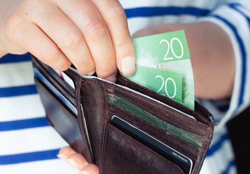 Close-up image as a woman takes money from a wallet.