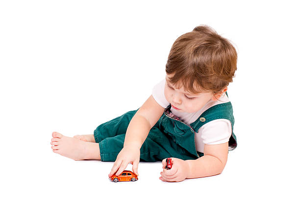 Little cut boy playing with two toy cars. Isolated on white.