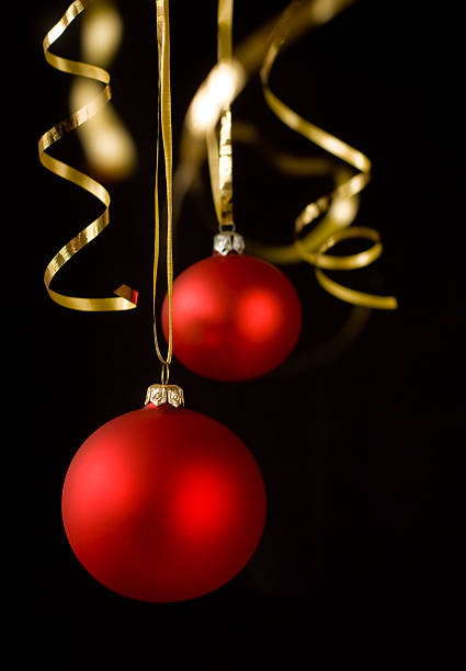 Red christmas balls and golden ribbons isolated on black.
