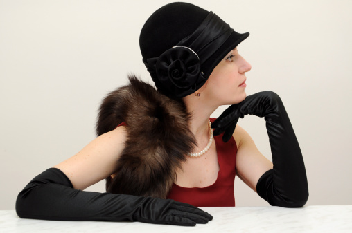 Young beautiful lady in black retro hat and gloves sitting in a profile waiting pose